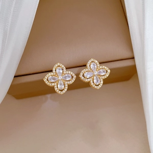 Macro shot of gold four-leaf clover earrings with pear-shaped cubic zirconia and pavé stones