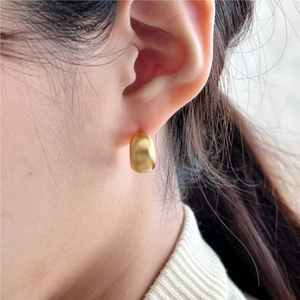 Minimalist matte gold U-shaped silver hoop earring worn by a model in a side view profile