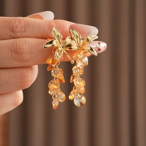 Macro shot of vintage gold flower tassel earrings with orange crystal beads held in hand