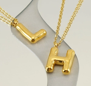 Gros plan des pendentifs lettres L et H style ballon avec finition dorée polie
