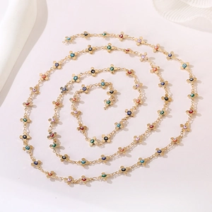 Detailed view of golden chain necklace with colorful evil eye cross charms in a spiral layout