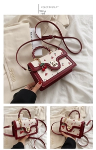 Close-up of the cherry print handbag with a unique petal-shaped metal twist lock