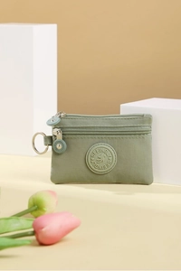 Detailed close-up of sage green nylon mini coin purse with double zippers and metal key ring