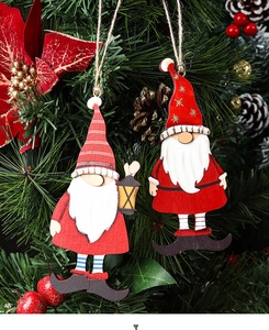 Detail of two wooden Christmas gnome ornaments hanging on a tree with red berries and pine cones