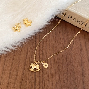 Macro detail of gold plated pony necklace and stud earrings set on a wooden surface