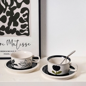 Detail of vintage hand-painted floral ceramic coffee cup with saucer and steel spoon