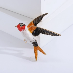 Detailed view of colorful swallow brooch featuring intricate enamel craft and gold accents