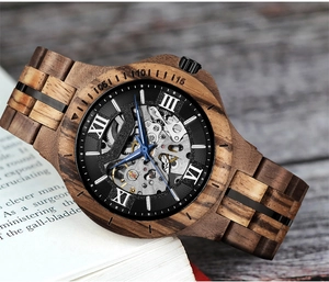 Detail of skeleton dial wooden mechanical watch with blue hands and Roman numerals
