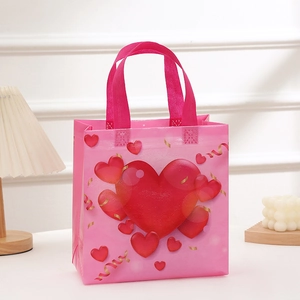 Pink non-woven Valentine's gift bag with red hearts and golden ribbon handles