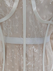 Macro view of white lace floral patterns and polka dot mesh fabric with supportive piping