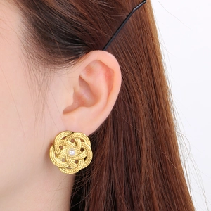 Détail d'un mannequin portant des boucles d'oreilles dorées avec perle blanche