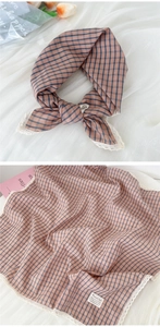 Detail of pink-brown plaid cotton linen scarf with delicate white lace trim and floral accents