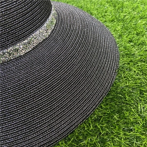 Close-up of black straw sun hat featuring sparkling rhinestone band and woven texture
