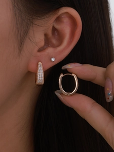 Macro detail of rose gold horseshoe earrings featuring pave-set white round cubic zirconia