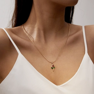 Close-up of gold tulip pendant necklace with red and green crystals on model
