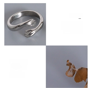 Detail of silver hugging hands ring made of surgical titanium steel with 18K gold plating