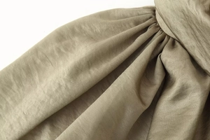 Macro shot of olive green satin fabric texture on bomber jacket with silky finish