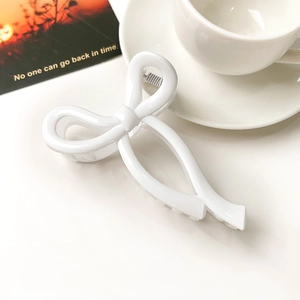 Close-up of a white bow claw clip made of glossy acrylic with minimalist aesthetic styling