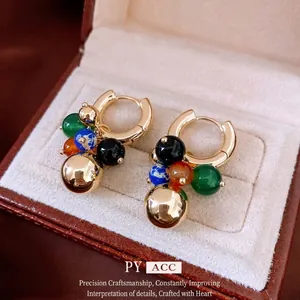 Boucles d'oreilles créoles dorées avec perles colorées sur velours beige dans un écrin