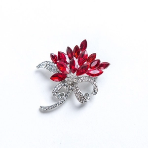 Detail shot of red crystal petals and silver bowknot brooch with clear rhinestones