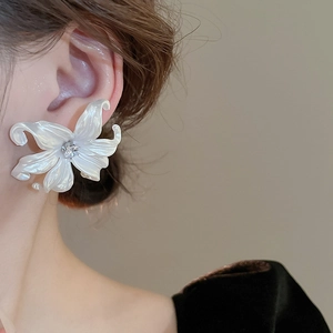 Detailed view of white lily earrings with pearl luster and a sparkling zircon center