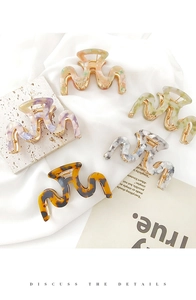 Detail of five assorted marble pattern hair claws with strong metal springs on satin