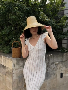 Détail de la robe en dentelle blanche avec chapeau de paille et sac tissé en vacances