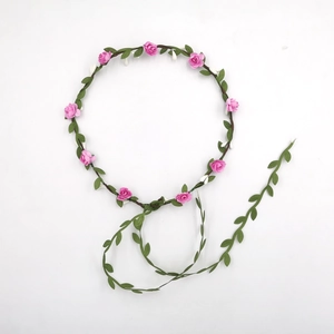 Handmade flower crown with pink roses and green leaves on a brown woven vine headband