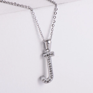 Macro shot of silver letter J pendant with sparkling rhinestones on polished metal
