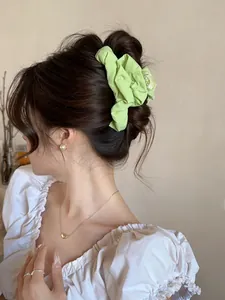 Detail view of light green pleated fabric hair claw clip worn on a model hair