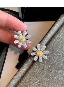 Macro shot of silver daisy earrings with yellow center and sparkling zircon stones