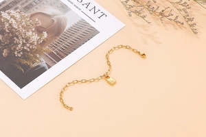 Detailed macro of gold padlock charm with star engraving on link chain bracelet