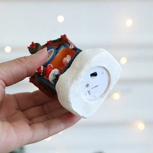 Bottom view of glowing resin Christmas cottage with battery compartment and power switch