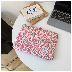Floral quilted laptop sleeve with pink flowers and a white text label on a white table