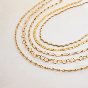 Detailed flat lay of five different golden stainless steel snake and paperclip chains