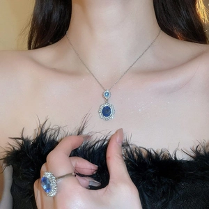 Detail of blue oval gemstone necklace and ring set with sparkling diamond halo