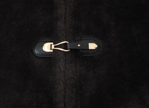 Macro detail of gold metal fastener on black textured wool jacket with leather base