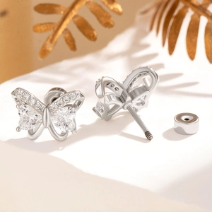 Silver bow stud earrings with sparkling cubic zirconia on elegant beige background