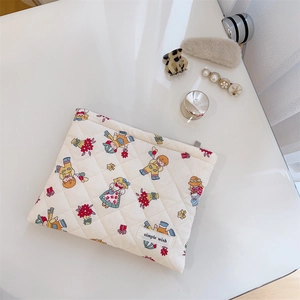 Detail view of quilted cotton makeup bag with cute floral characters and woven label