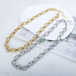 Detailed view of gold and silver chunky rope chains with love pendants on a ceramic tray
