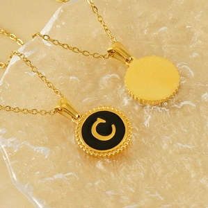 Titanium steel necklace with gold letter C pendant on a textured glass surface