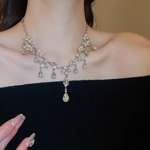 Close-up of sparkling silver necklace with leaf and teardrop crystal pendants on model