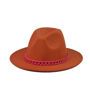 Detail of a bright orange fedora hat featuring a stylish hot pink chain decoration