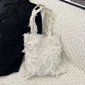 Macro shot of white canvas tote with intricate diamond fringe texture and woven handle
