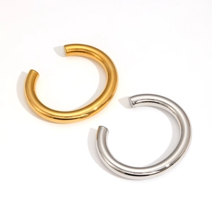Detailed view of chunky polished gold and silver open cuff bracelets on white background