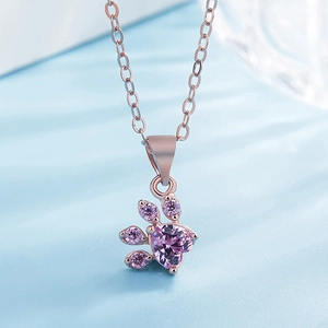Macro shot of rose gold paw print pendant with heart-shaped purple gemstone detail