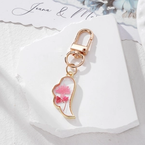 Detailed close-up of handmade pink dried flower resin heart charm with gold lobster clasp