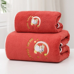 Detailed embroidery of a cartoon rabbit on a soft red coral fleece bath towel surface