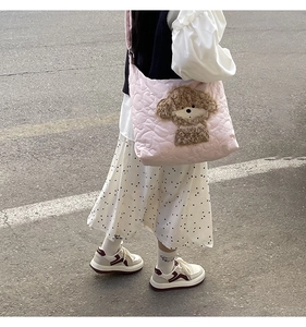 Pink quilted shoulder bag with brown teddy bear embroidery shown in a street style shot