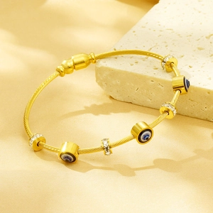 Gold evil eye steel cable bracelet with pavé crystal beads and bohemian spiral design